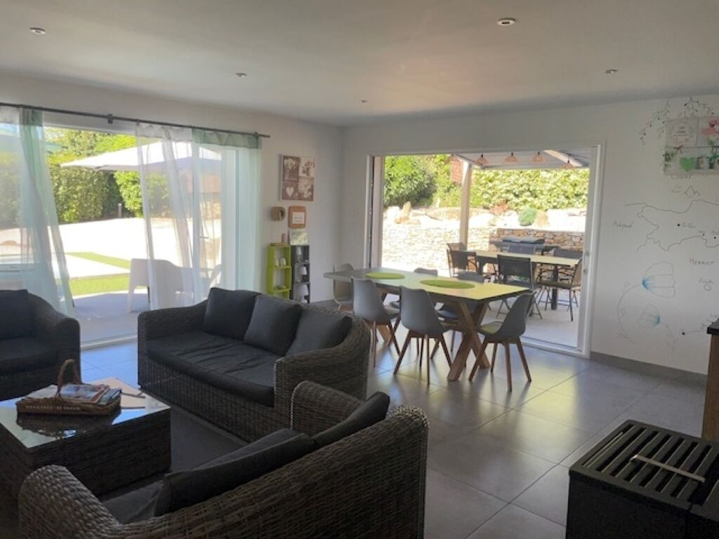 Uma sala de estar ampla, com sofá, poltronas e um espaço de refeições com mesa e cadeiras.