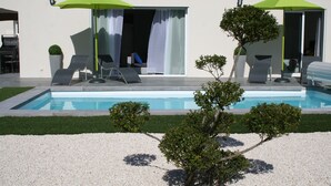 A modern house with a swimming pool, outdoor seating, and a well-maintained garden.