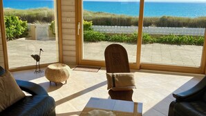 A modern living room with a large glass door leading to a balcony with a view of the ocean.
