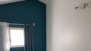 A bedroom with a bed, curtains, a nightstand, and a wall-mounted light fixture. - House located in the countryside (Mollégès)