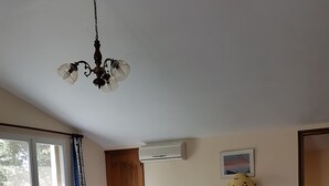 A living room with a sofa, a wooden dining table with chairs, a yellow vase, and a ceiling light fixture. - House located in the countryside (Mollégès)