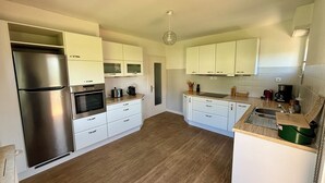 A modern kitchen with white cabinets, stainless steel appliances, and a wooden floor. - 3 Storks, House 9 acres, Alsace Centre (Châtenois)