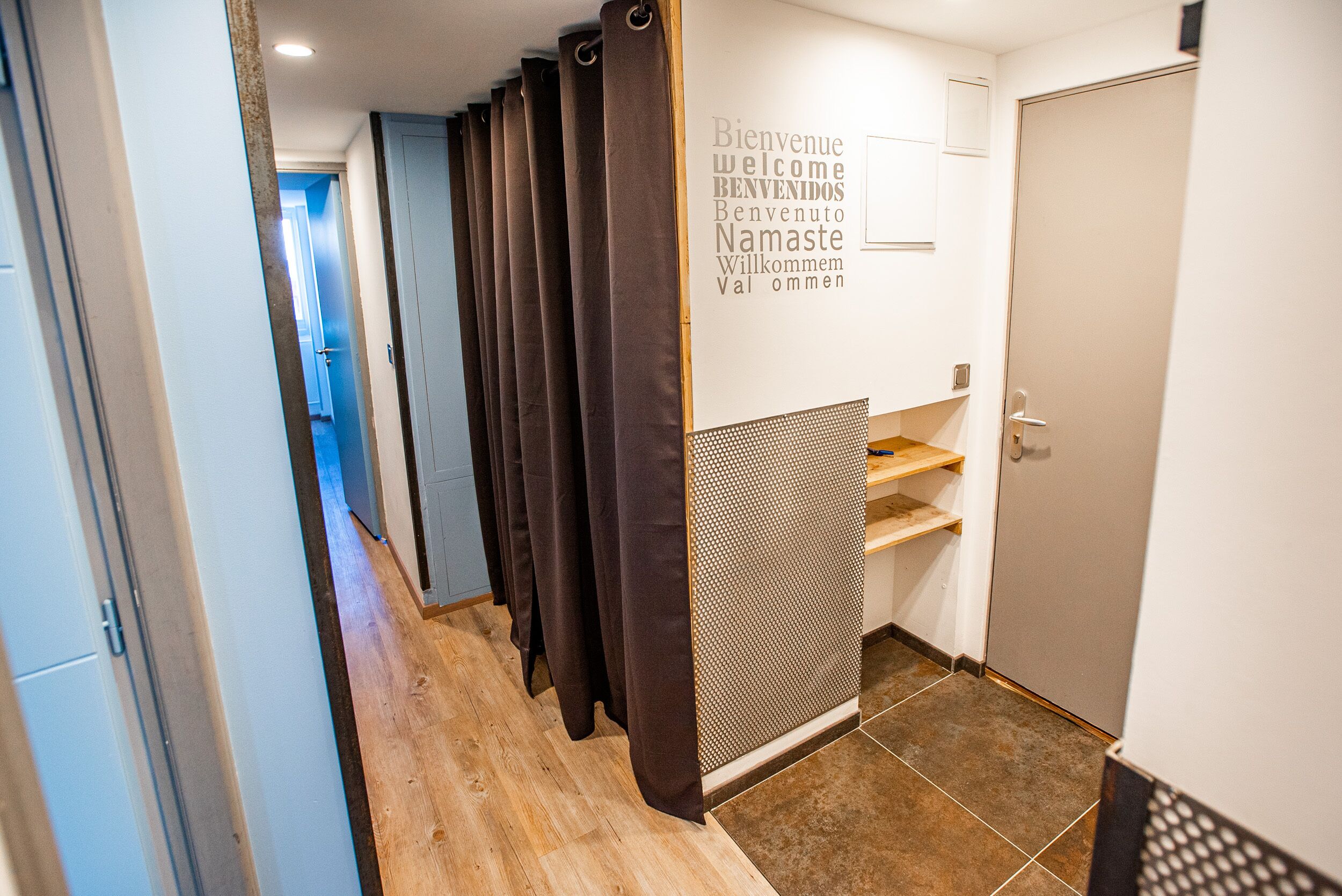 A hallway with a reception desk, a wall with a welcome sign, and a door.