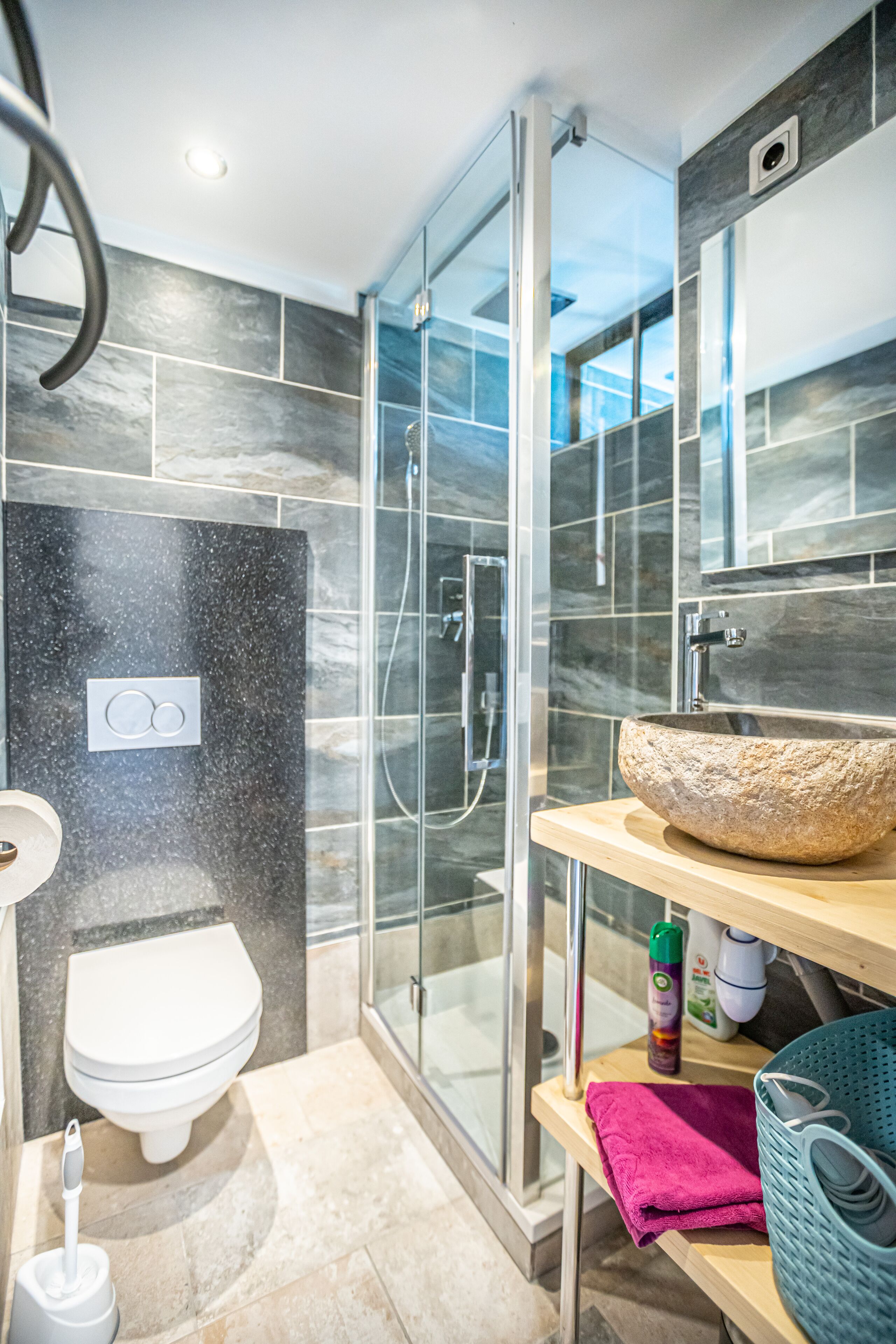Un bagno moderno con doccia vetro, lavabo in pietra e un water.