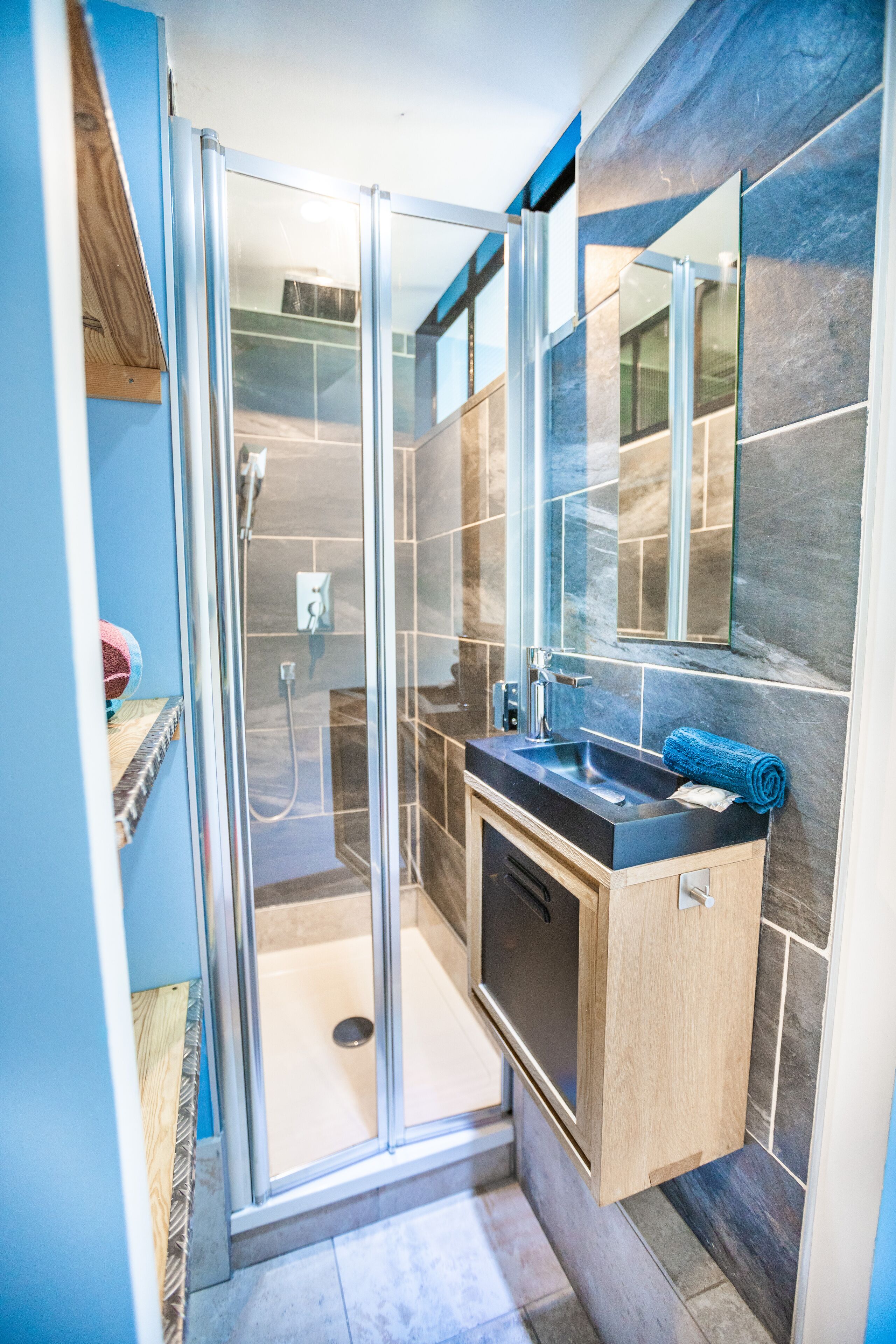Une salle de bain moderne avec une douche à parois de verre, un meuble-lavabo en bois et un grand miroir.
