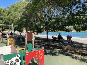 Children can play on the climbing frame and slide in this outdoor play area, while adults relax on the shaded bench.