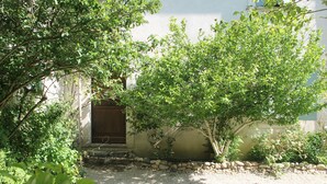 Un bâtiment avec une allée gravillonnée, un mur en pierre et une porte en bois.