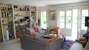 Un salon avec un canapé gris, des étagères, une table basse et un téléviseur.