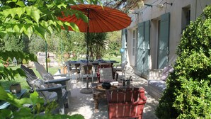 Une terrasse extérieure avec une table, des chaises et un parasol.