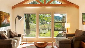 A spacious living room with a high ceiling, large windows, and a view of a vineyard. - Private 3-Acre Vineyard Estate with Extraordinary Views (Sebastopol)