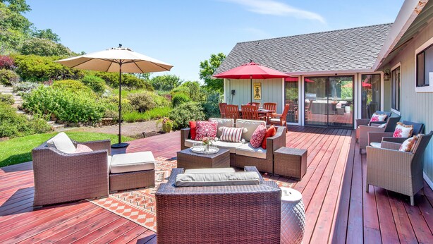 A covered outdoor patio with wicker furniture, a red umbrella, and a dining area with a table and chairs. - Private 3-Acre Vineyard Estate with Extraordinary Views (Sebastopol)
