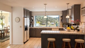 A modern kitchen with a large island, dark cabinets, and a view of the outdoors. - Private 3-Acre Vineyard Estate with Extraordinary Views (Sebastopol)