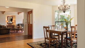 A dining area with a wooden table, chairs, and a chandelier. There is a view of greenery outside the window. - Private 3-Acre Vineyard Estate with Extraordinary Views (Sebastopol)