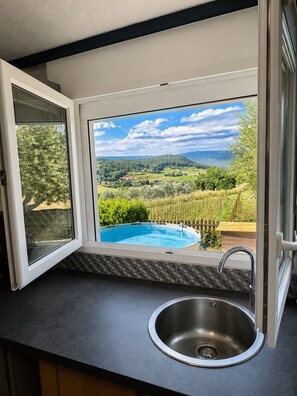 A kitchen with a view of a swimming pool and countryside.