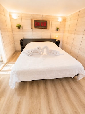 A hotel room with a bed, a sign reading 'ON AIR,' and a wall-mounted light fixture.