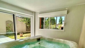 Een hottub met een helder uitzicht op de omliggende tuin en een huis op de achtergrond.