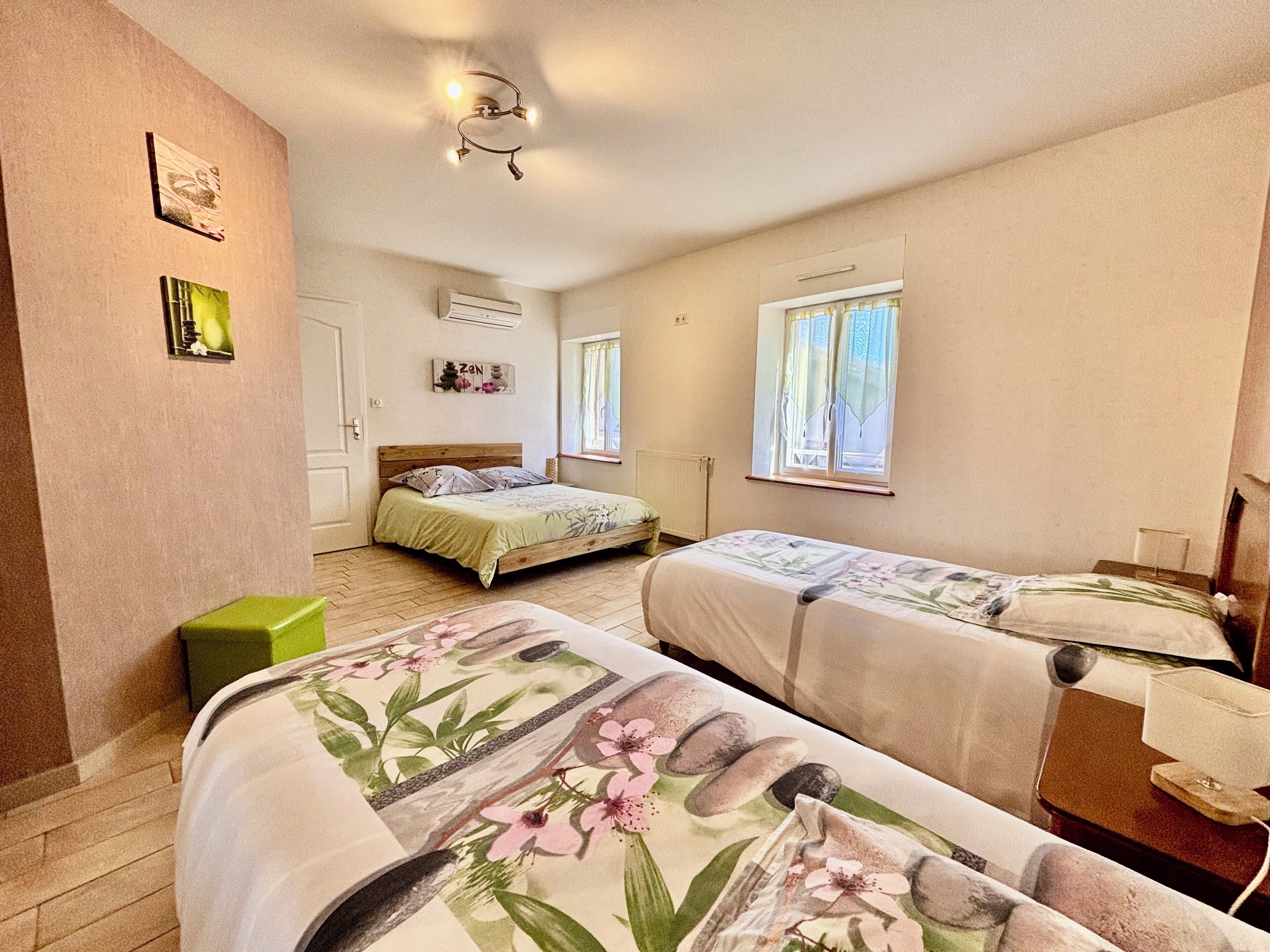 Une chambre avec deux lits, une fenêtre, une table de chevet et un climatiseur fixé au mur.
