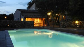 A swimming pool with a stone wall and a house in the background.