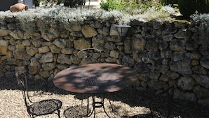 Un mur de pierre avec une table ronde et quatre chaises dans une cour.