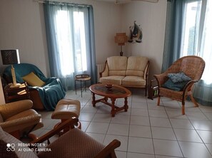 Ein Wohnzimmer mit einer Couch, Sesseln, einem Couchtisch und einer Lampe.