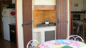 Une cuisine avec des portes en bois, un pare-feu en carrelage, une petite plante en pot et un coin repas avec une table et des chaises.