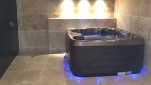 A modern bathroom with a black jacuzzi tub, illuminated by blue lights, and a large mirror above. - Superb high standing villa Pinarellu (Zonza)