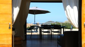 An open doorway leading to a terrace with a table, chairs, and an umbrella. - Superb high standing villa Pinarellu (Zonza)