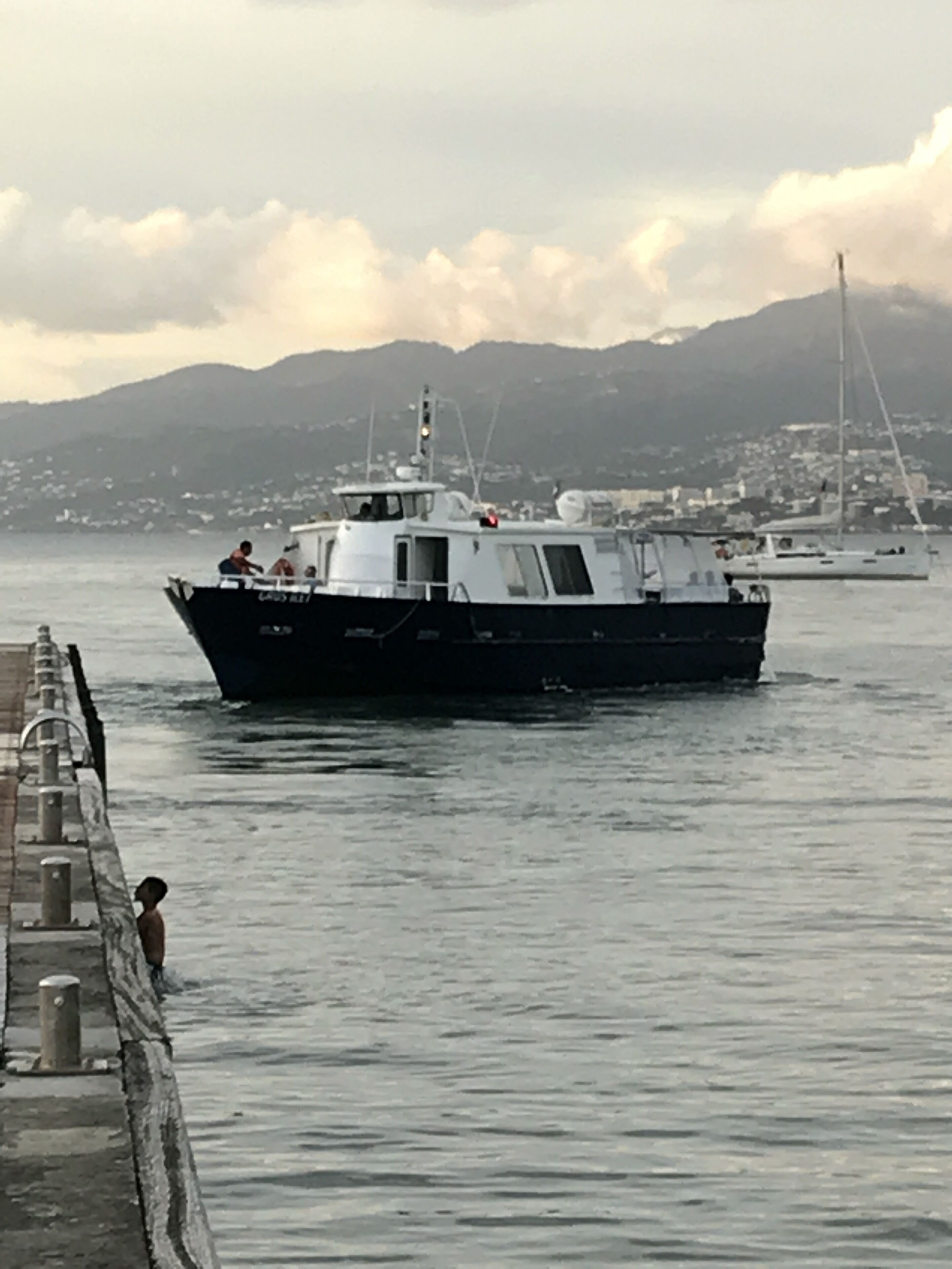 Un barco amarrado en un muelle, con un paisaje montañoso al fondo.
