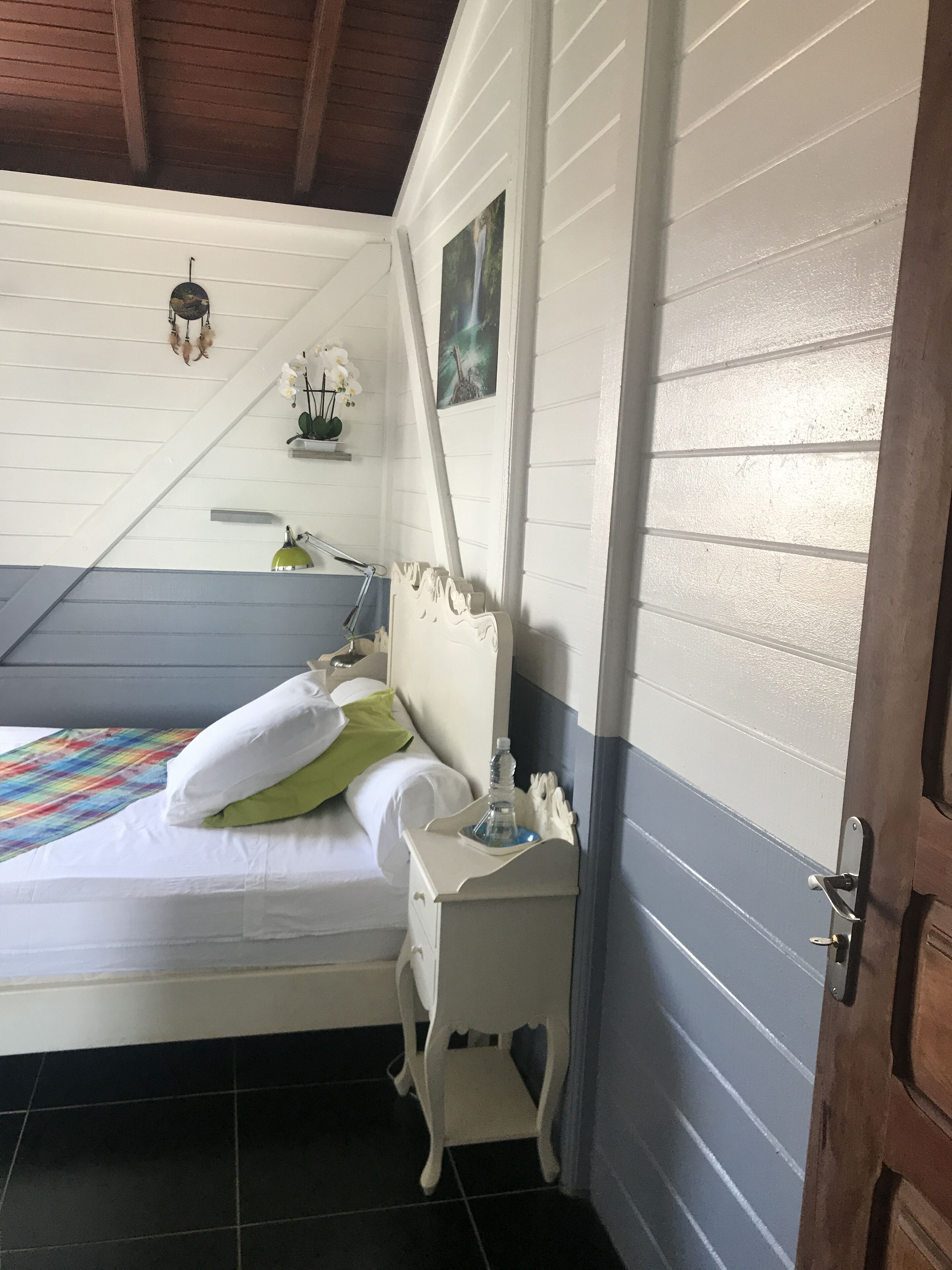 Ein Schlafzimmer mit einem Bett, einem Nachttisch, einer Wandleuchte und einer Tür.