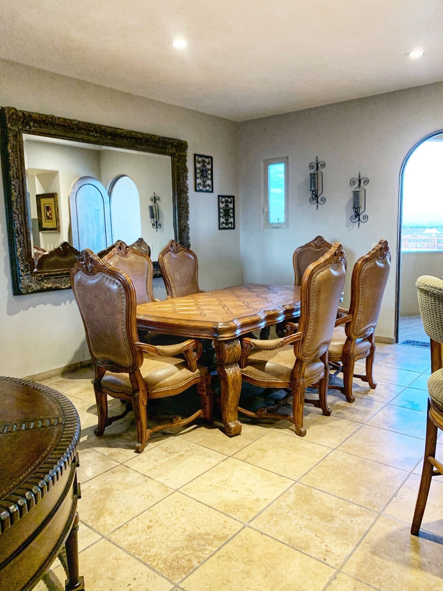 A dining room with a large wooden table surrounded by six upholstered chairs.