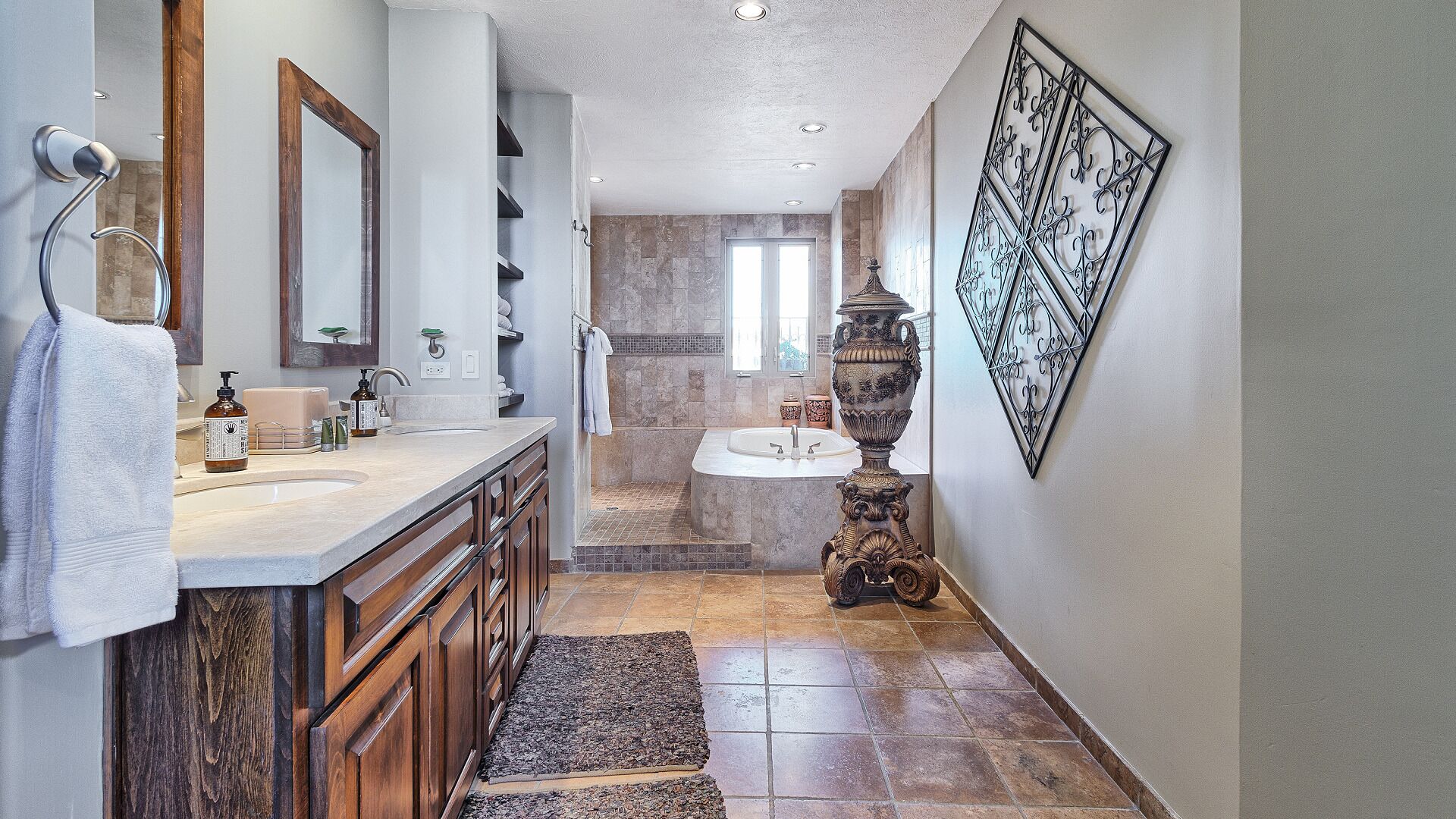 Un baño moderno con un tocador de madera, un espejo grande, un jarrón decorativo y una obra de arte en la pared.