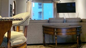 Ett vardagsrum med en takfläkt, en soffa, ett träbord och utsikt genom en skjutdörr av glas.