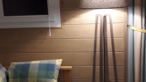 Ett rum med en säng, en golvlampa, ett fönster och en vägg som är klädd med träpanel.