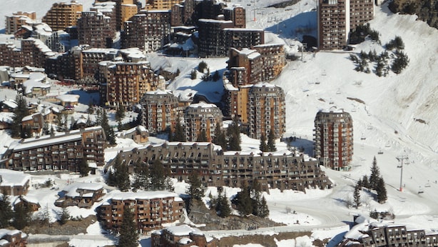 Ett snötäckt bostadsområde med flera hyreshus, skidliftar och en skidbacke.
