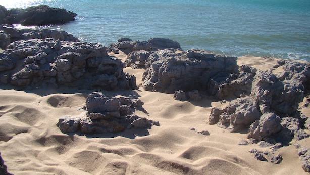 A rocky beach with clear water and no visible structures. - Small house, air conditioning and shaded garden, in a quiet area near the beach (Fleury)