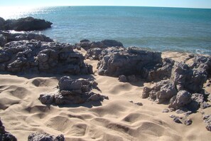 Una playa rocosa con aguas claras y sin construcciones a la vista.