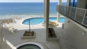 Un espace piscine doté d’un jacuzzi, de chaises longues et offrant une vue sur l’océan.