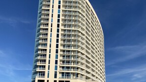 Un hôtel de grande hauteur doté de nombreux balcons, d’un toit plat et donnant sur une plage de sable.