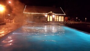 Relax by the illuminated pool surrounded by a charming standalone structure.