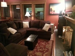 Relax in this inviting living space with a comfortable sofa, ottoman, and TV.