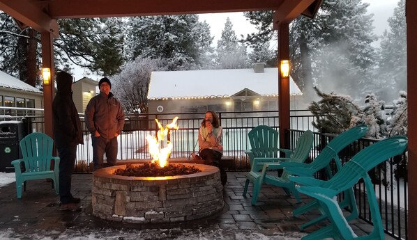 Relax by the fire pit in a cozy outdoor seating area under a covered roof.