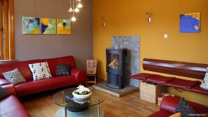 A living room with a red sofa, a glass coffee table, a fireplace, and abstract art on the walls.