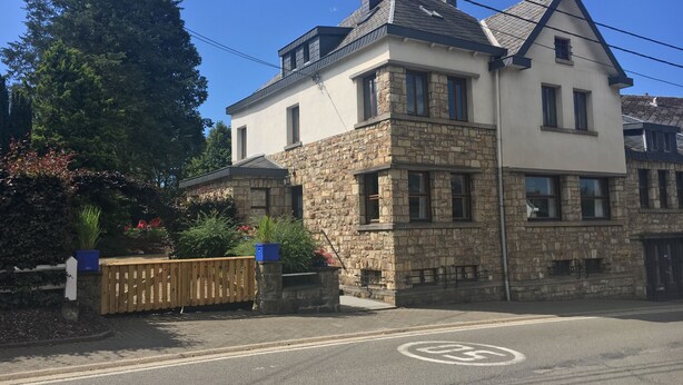 A two-story house with a stone facade and a gabled roof.