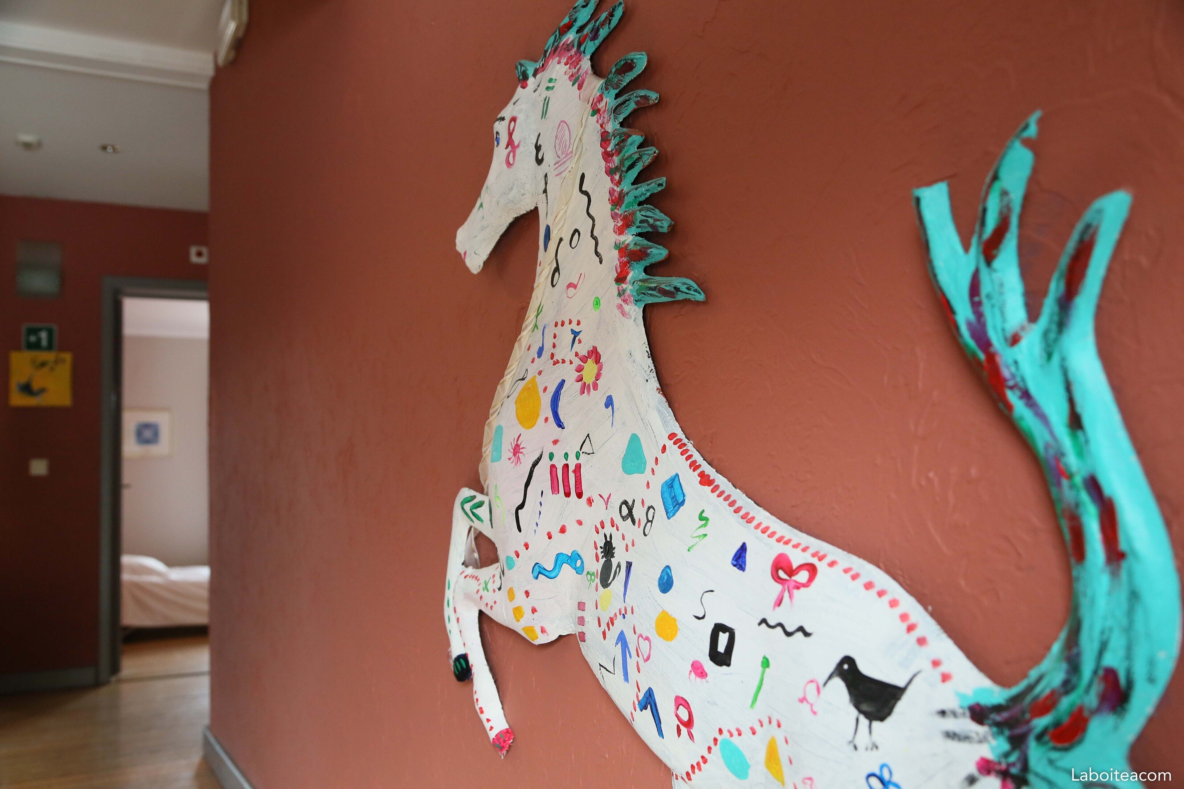Un mur orné d’une fresque colorée représentant un cheval et un oiseau.