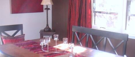 Una mesa de comedor con mantel rojo, una lámpara y varios vasos.