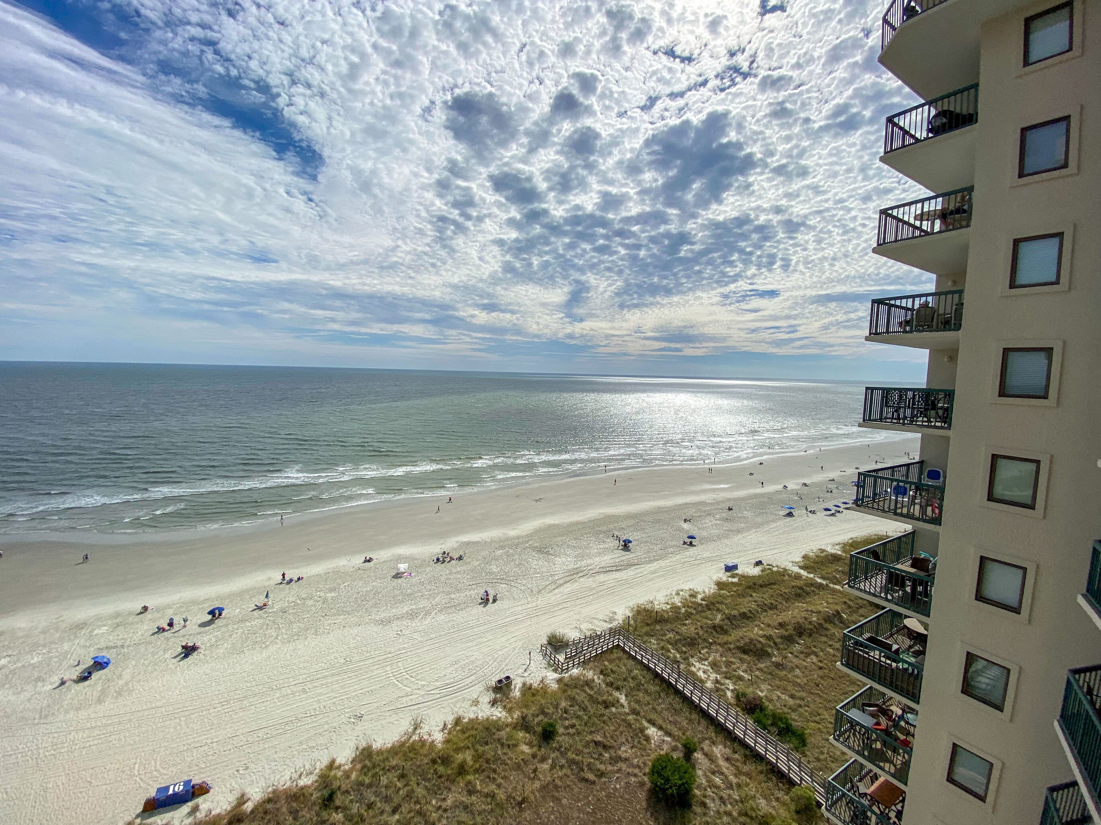Una spiaggia con vista sull'oceano e un edificio con balconi che si affacciano sulla spiaggia.