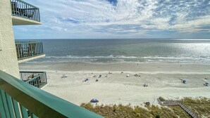Blick auf den Strand vom Balkon mit blauem Himmel und Meer.