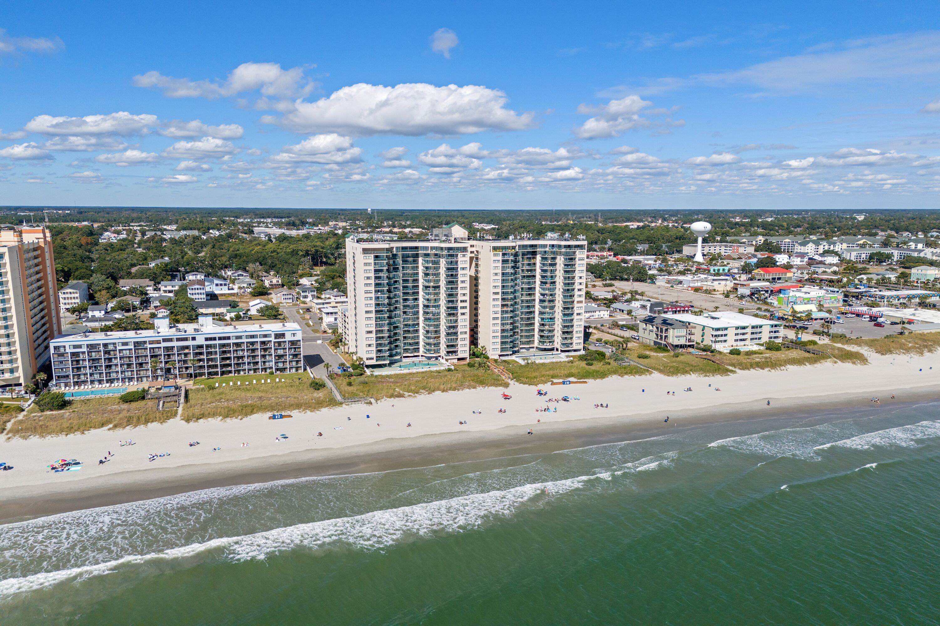 Eine Küstenstadt mit Hochhäusern, einem Sandstrand und blauem Himmel.