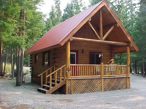 A wooden cabin with a porch and stairs leading to the entrance.