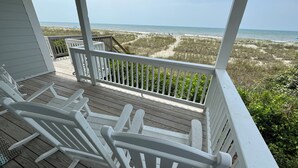 A wooden deck with white railings overlooking a beach. - Oceanfront Home (Holden Beach)